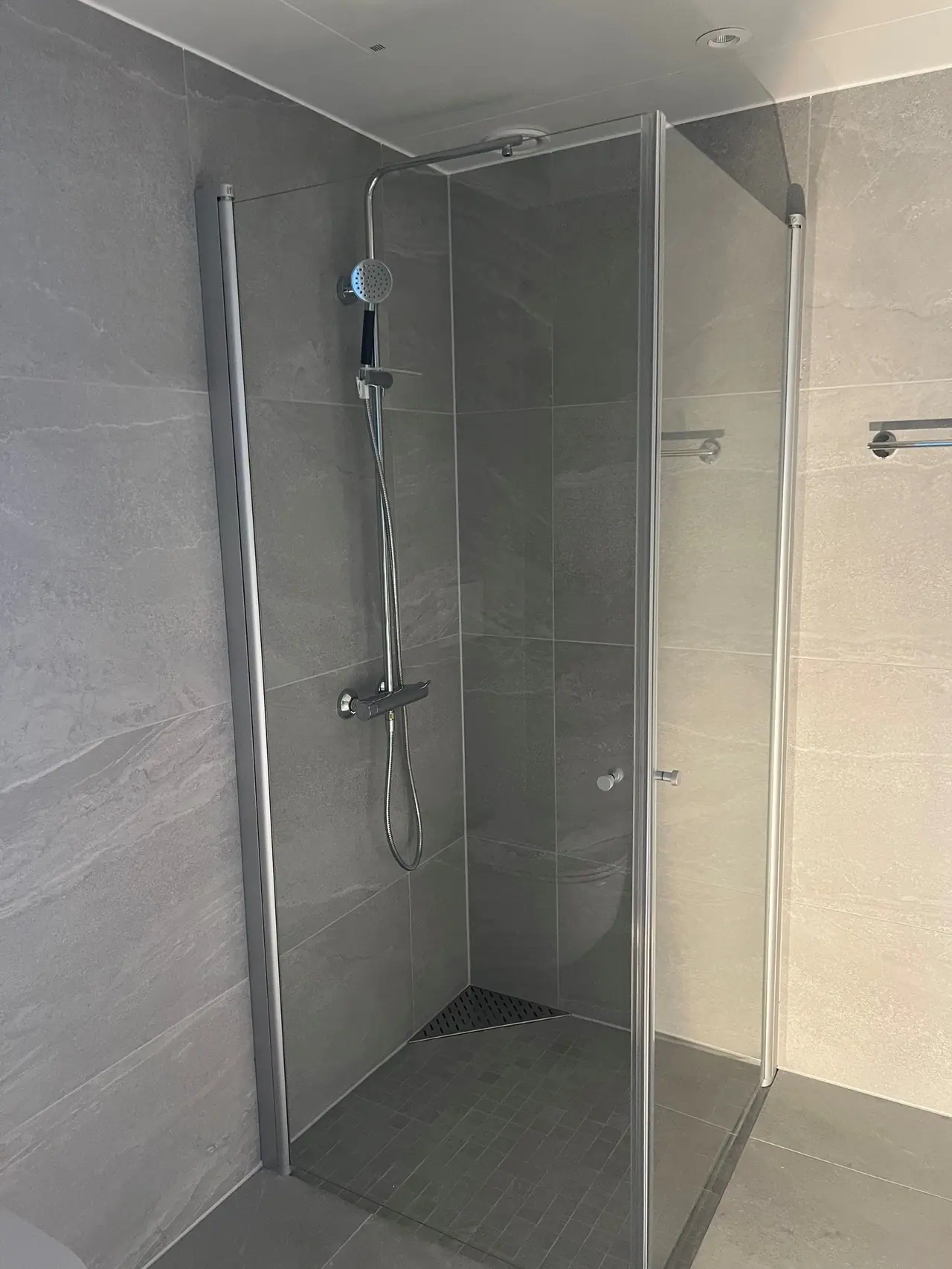 Bathroom with elegant 60x60 tiles and a corner shower with glass doors.