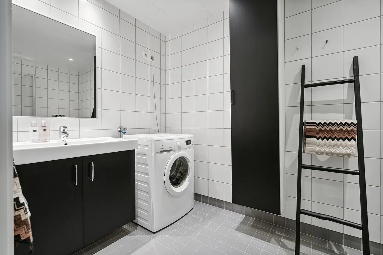 Modern bathroom with tiled walls and floor - Washing machine included.